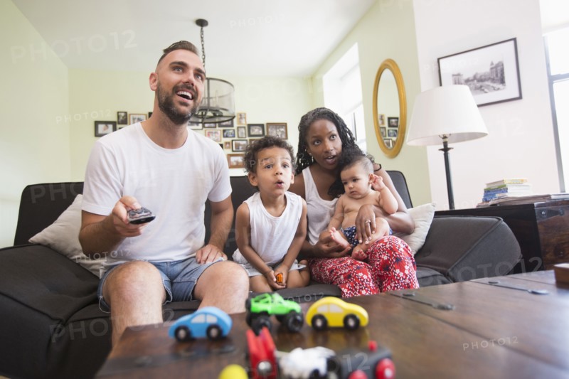 Parent watching television with son and daughter