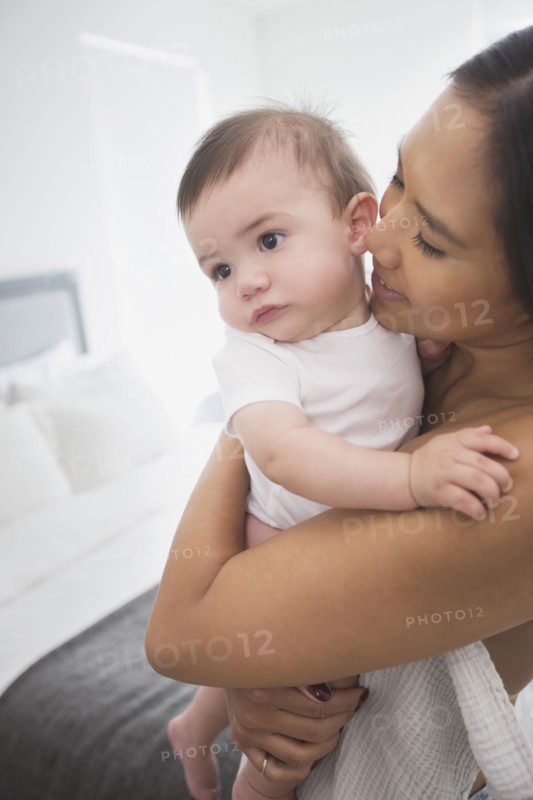 Mother hugging baby son in bedroom