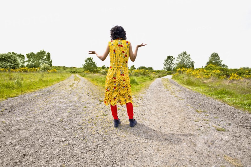 Asian woman shrugging at split in road