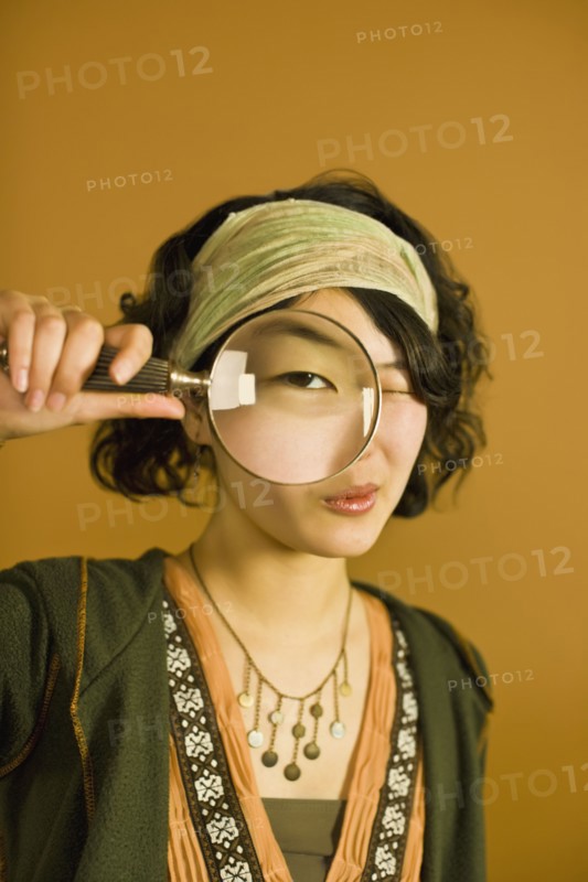 Asian woman looking through magnifying glass