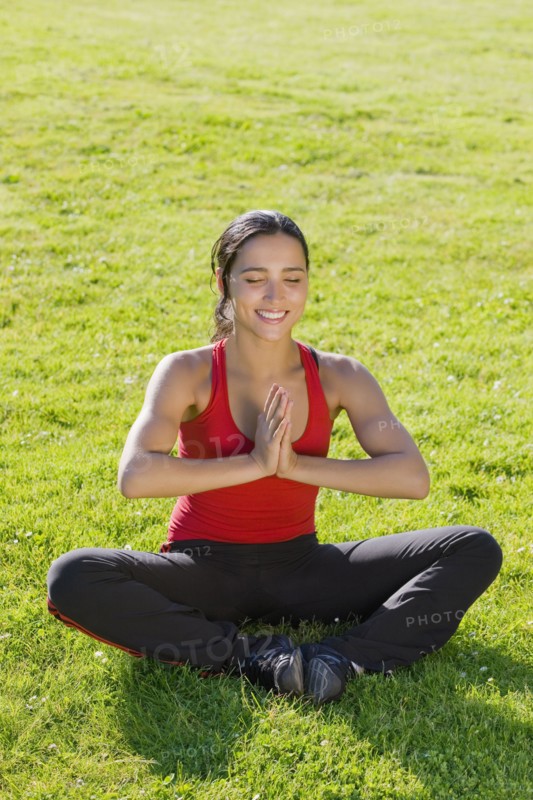 Hispanic woman practicing yoga in grass