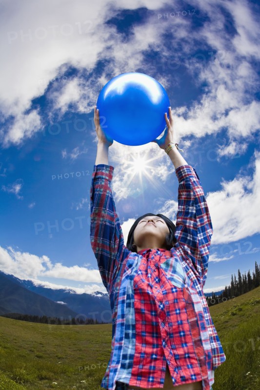 Asian man lifting ball in remote field