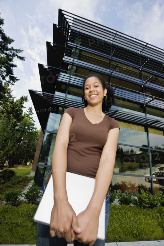 Mixed race woman holding laptop on campus outdoors