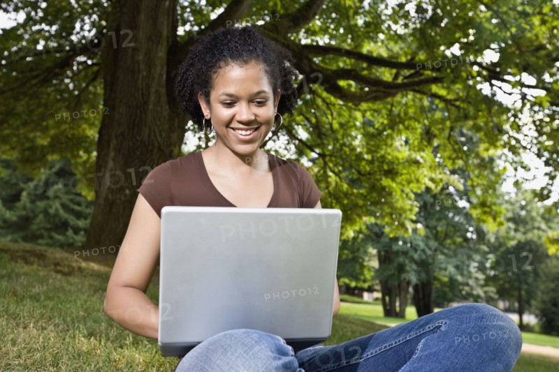 Mixed race woman typing on laptop outdoors
