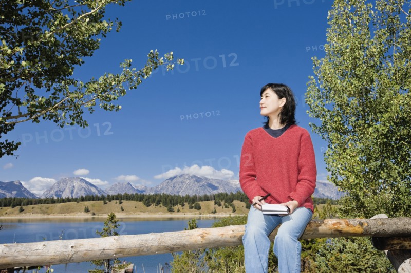 Japanese woman sitting on fence with mountains in background