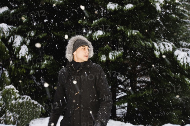 Mixed race man in hooded coat outdoors in snowfall