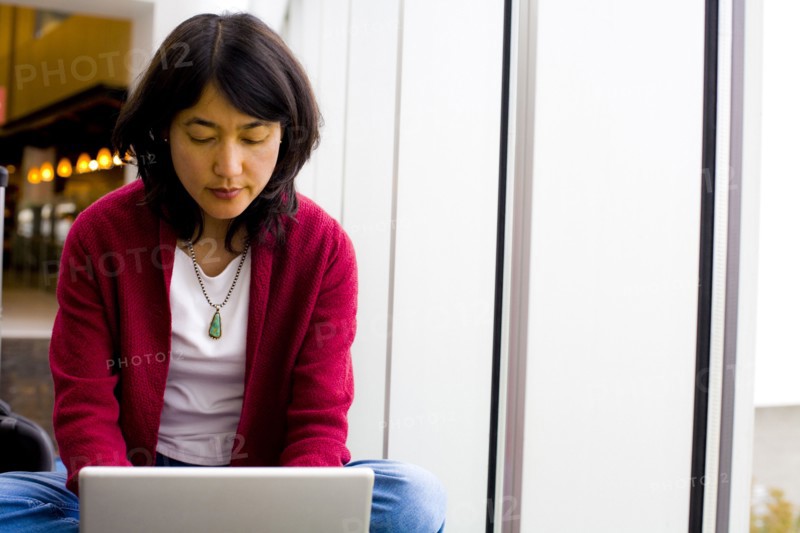 Japanese woman sitting cross-legged using laptop