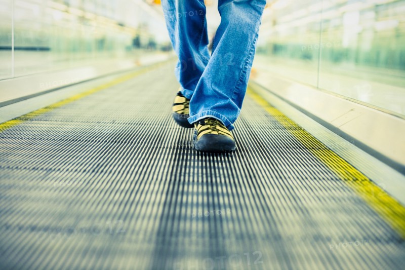 Legs of Japanese woman wearing jeans walking on moving walkway
