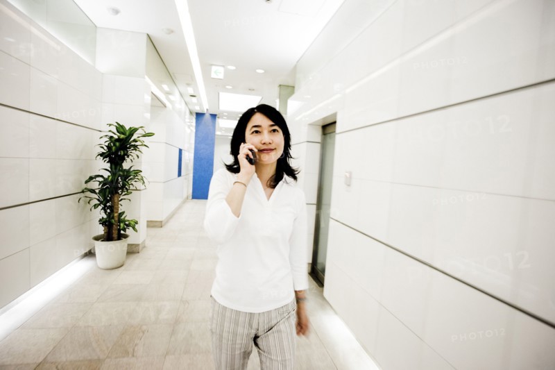 Japanese businesswoman talking on cell phone in corridor