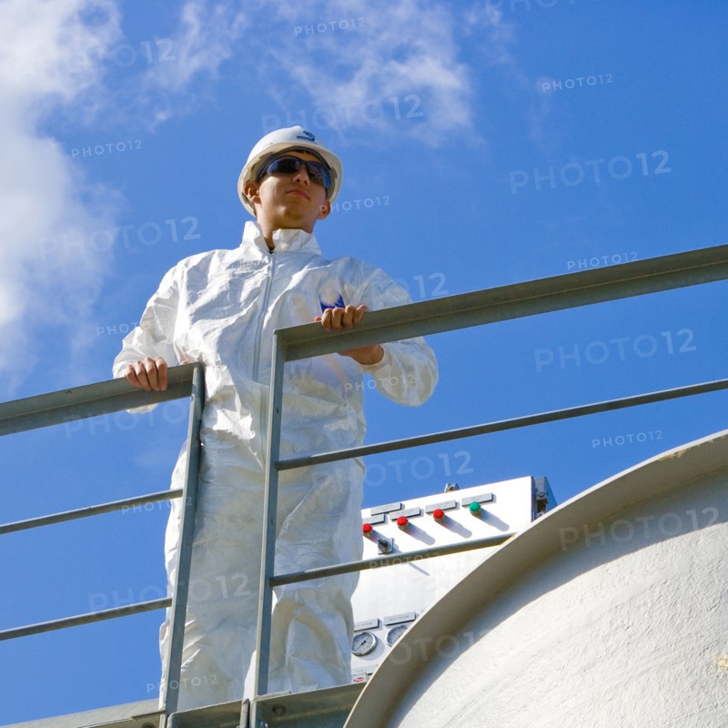 Caucasian man wearing coveralls leaning on railing