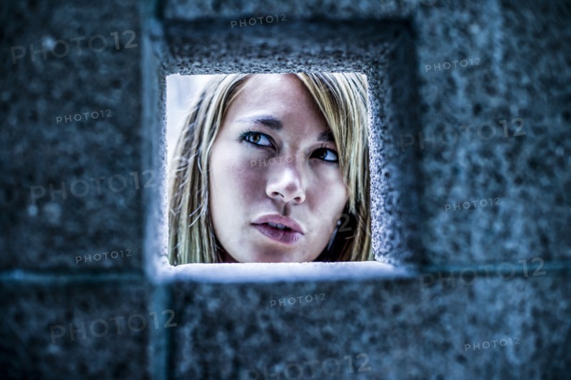 Curious Mixed Race woman looking through stone wall