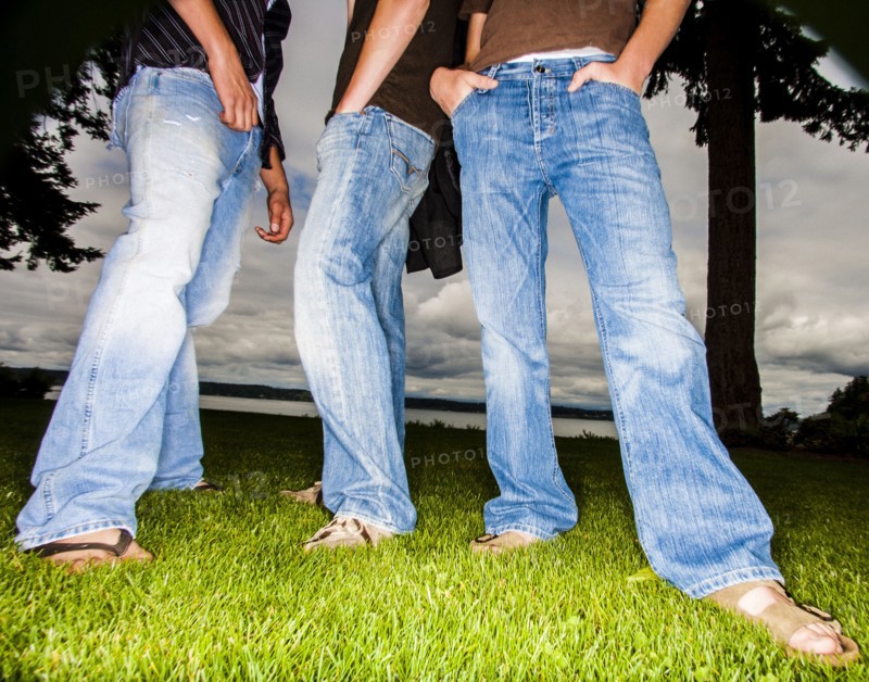 Legs of friends wearing jeans in grass