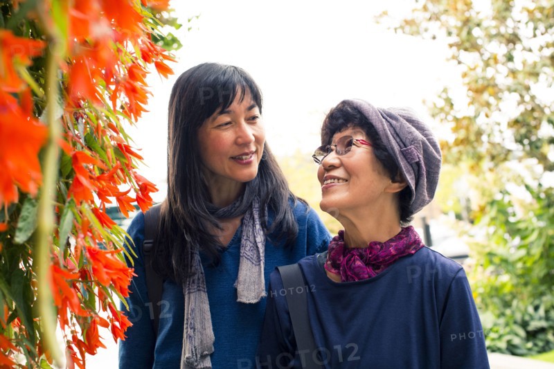 Older Japanese mother and daughter near autumn leaves