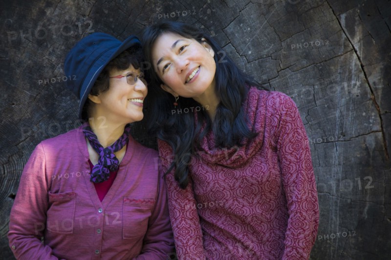 Older Japanese mother and daughter posing at tree slice