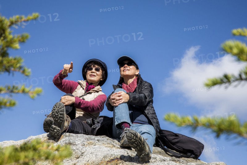 Older Japanese mother and daughter sitting on rock