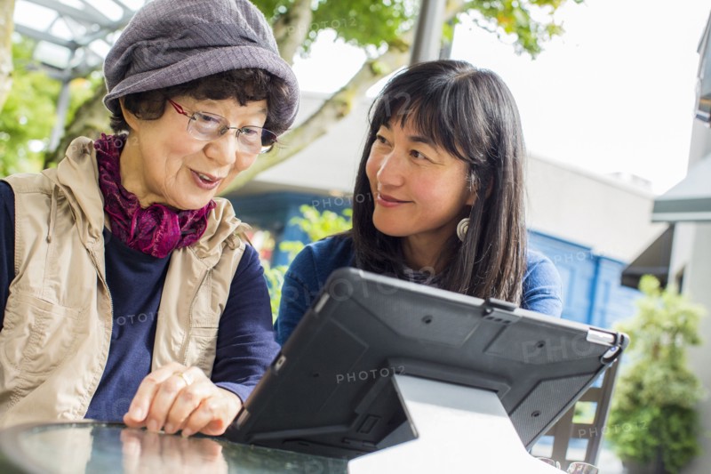 Older Japanese mother and daughter using digital tablet