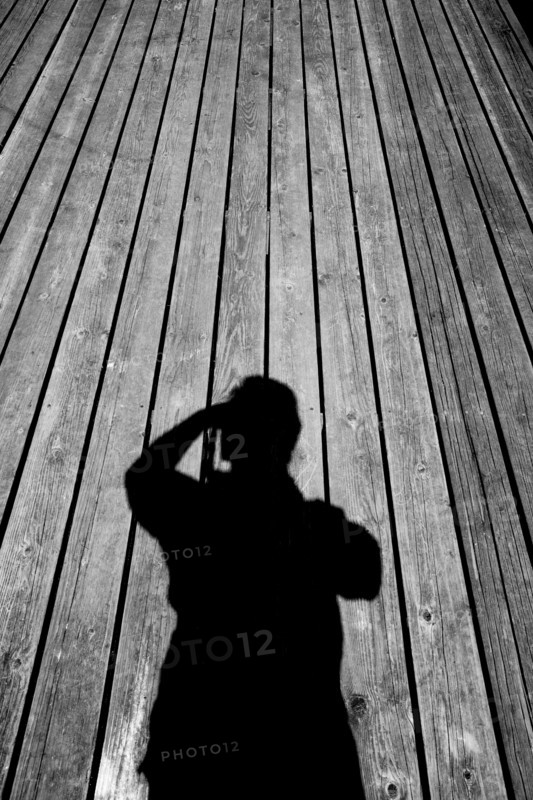 Shadow of Caucasian man with camera on wooden floor