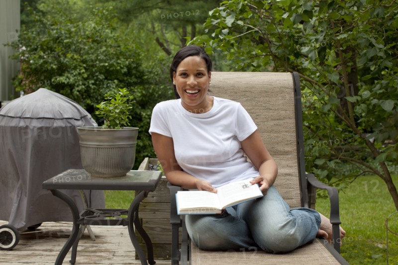 African American woman reading book in back yard
