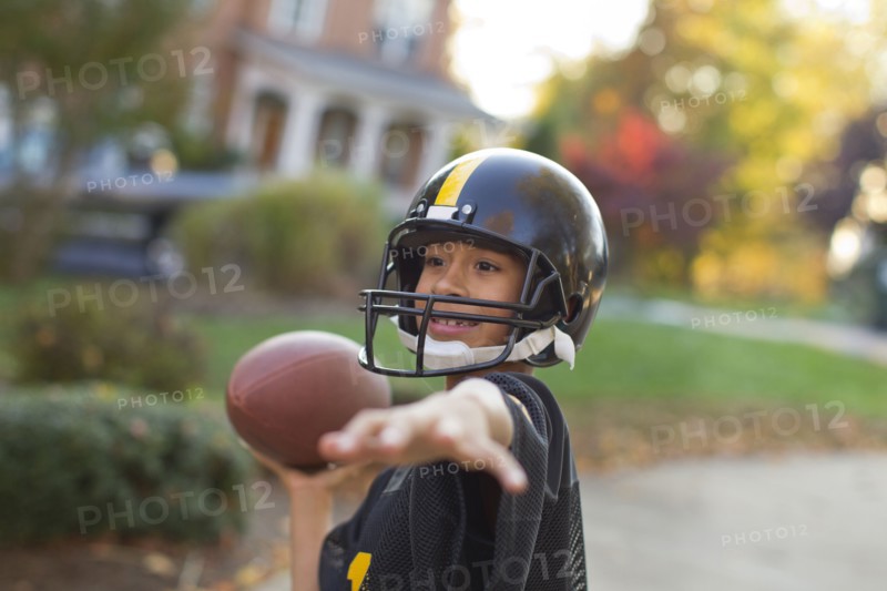 Mixed race boy playing football outdoors