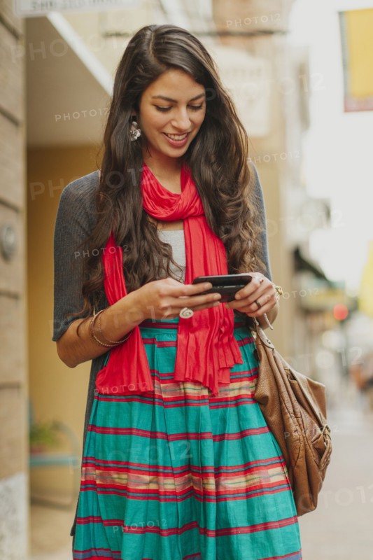 Mixed race woman using cell phone on city street
