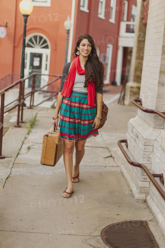 Mixed race woman carrying suitcase on city street