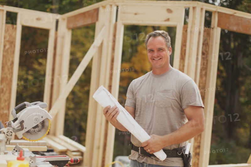 Caucasian construction worker holding blueprints on site