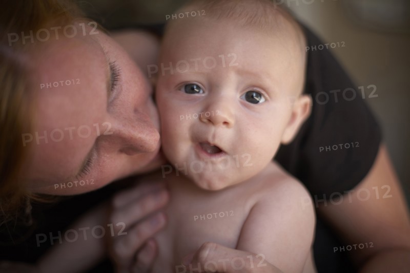 Caucasian mother kissing baby's cheek