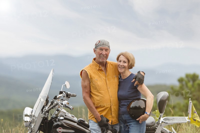 Older Caucasian couple smiling on motorcycle