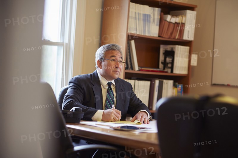 Mixed race businessman writing at desk in office