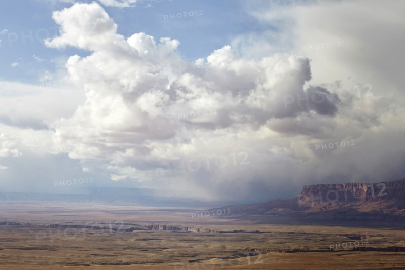 Puffy clouds rolling over rock formations in desert landscape