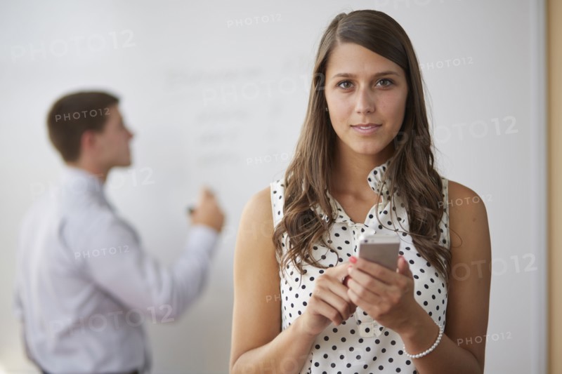 Mixed race businesswoman using cell phone in office