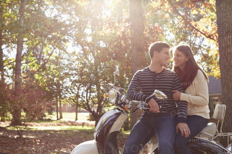 Couple sitting on scooter in park