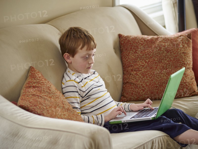 Caucasian boy using laptop on sofa