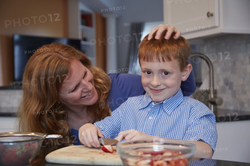 Caucasian mother and son chopping fruit in kitchen