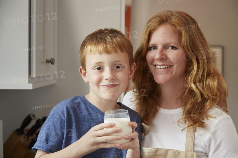 Caucasian mother and son drinking milk in kitchen