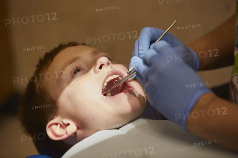 Pediatric dentist examining teeth of patient
