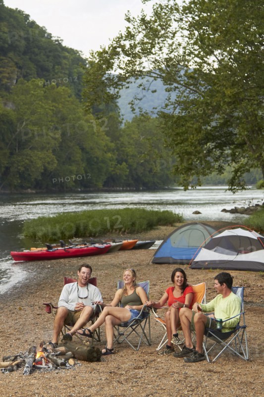 Friends relaxing around campfire at campsite