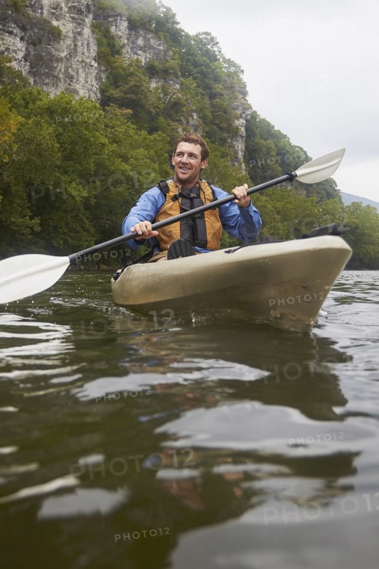 Caucasian man paddling kayak on remote river