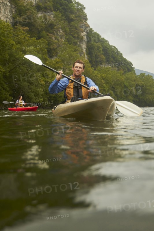 Caucasian man paddling kayak on remote river