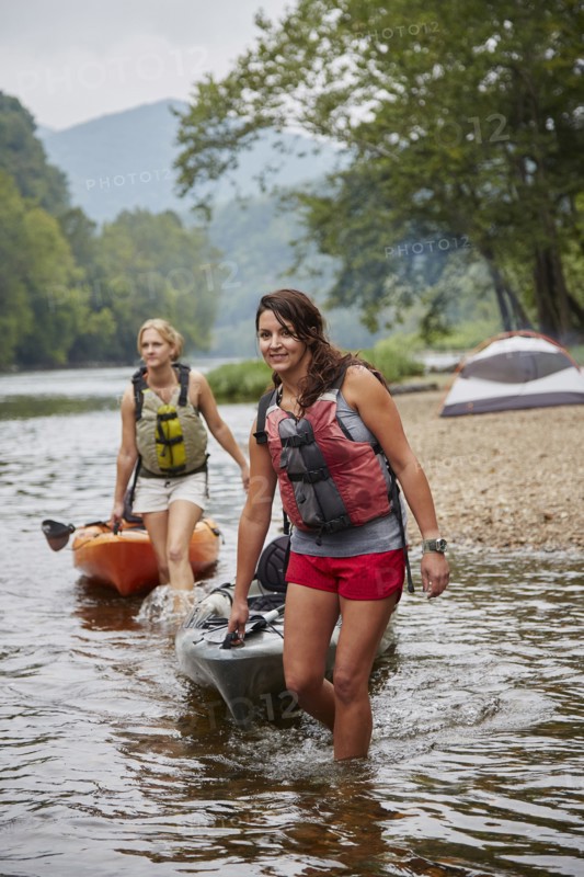 Women pulling kayaks in remote river