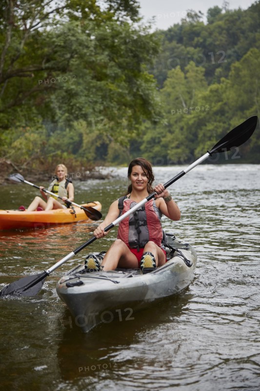 Women paddling kayaks in remote river