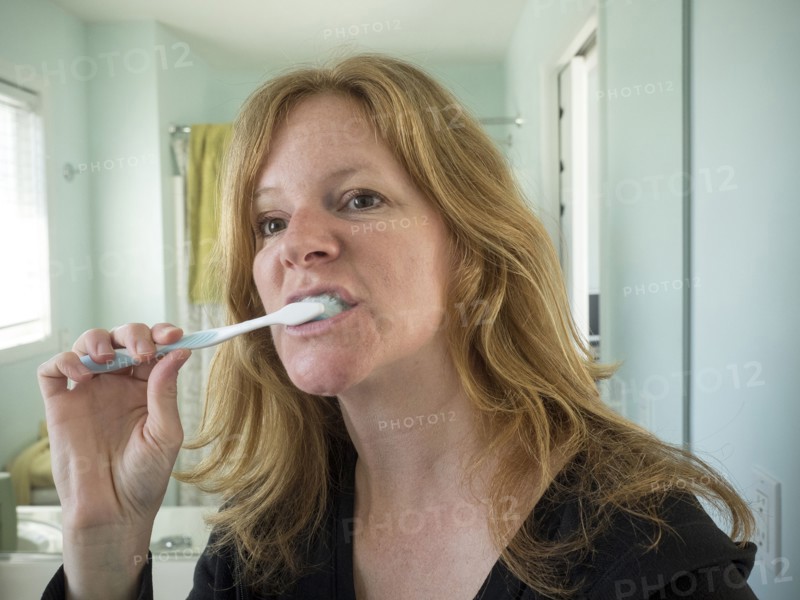 Caucasian woman brushing her teeth in bathroom