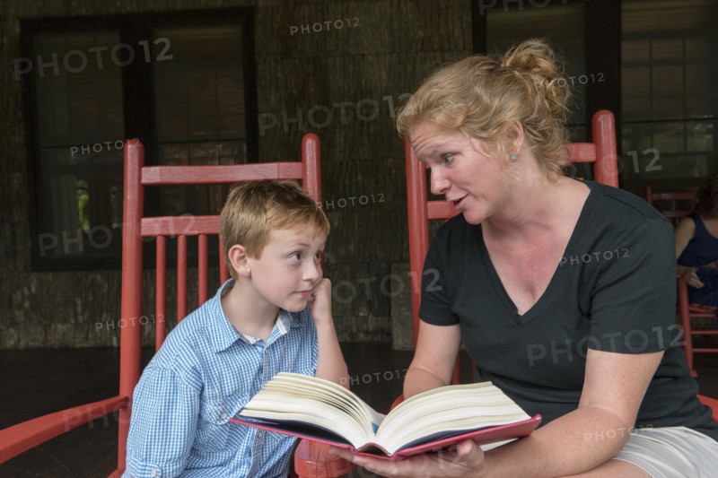 Caucasian mother and son reading on patio
