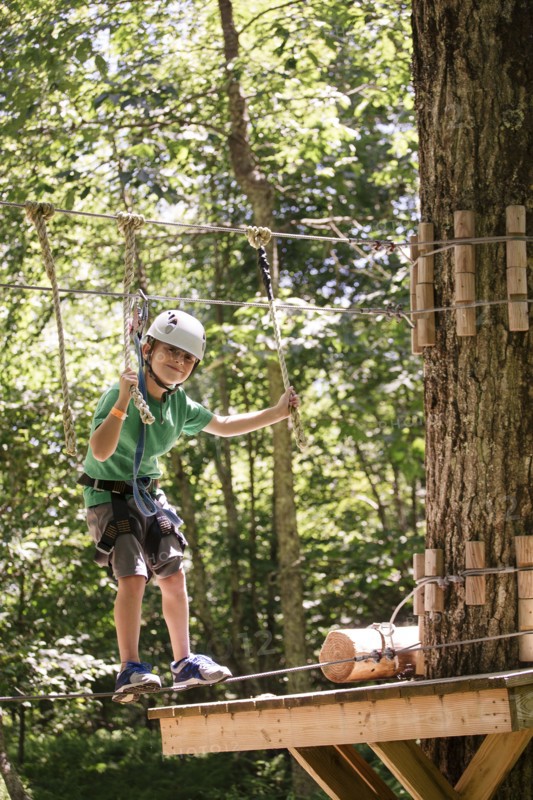 Caucasian boy balancing on slackline in forest