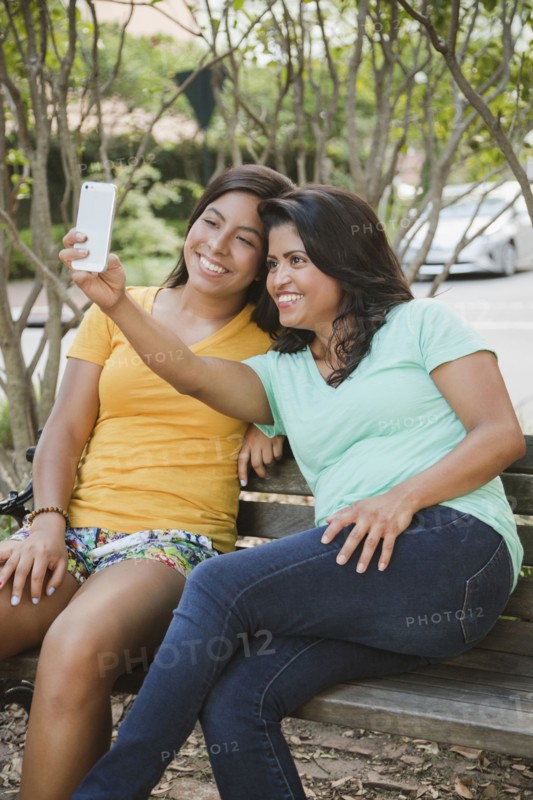 Hispanic mother and daughter posing for cell phone selfie