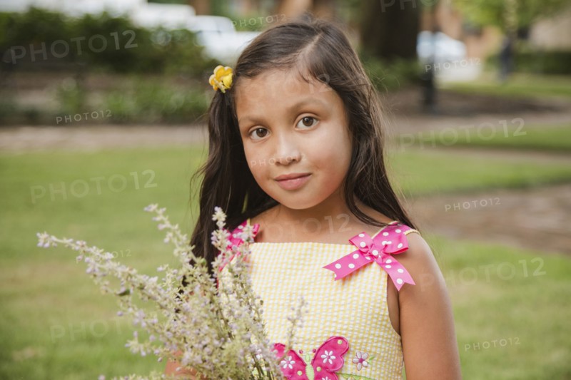 Hispanic girl holding flowers in park