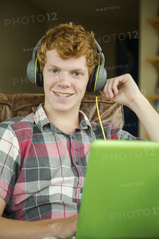 Portrait of smiling Caucasian boy listening to laptop with headphones