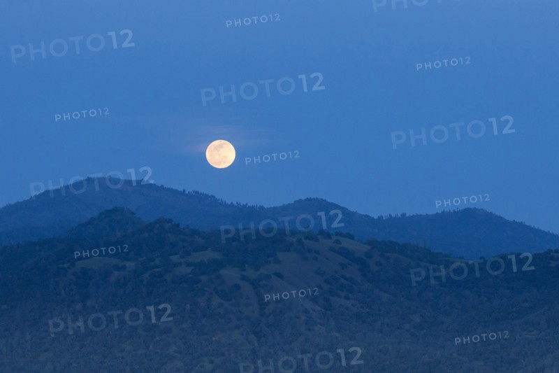 Glowing moon rising over foothills