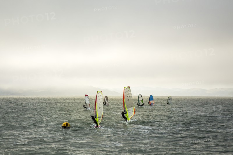 Windsurfers on ocean under cloudy sky
