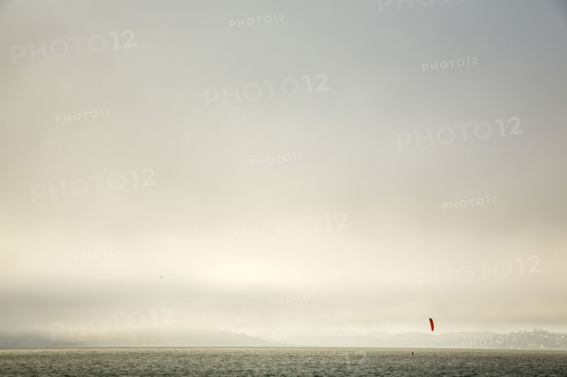 Kiteboarder on ocean under cloudy sky